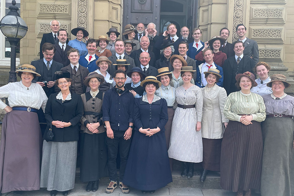 A big group of people dressed in period clothing stood on steps